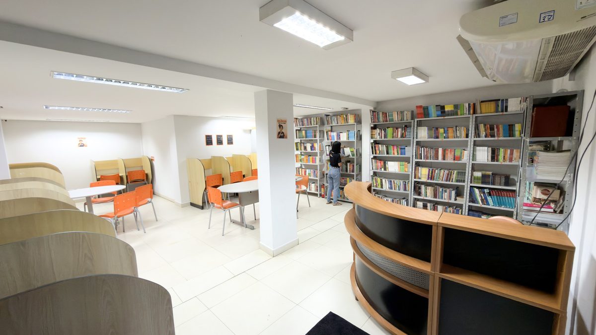 Biblioteca do Centro Educacional OMNI, com estantes de livros e cabines de estudo