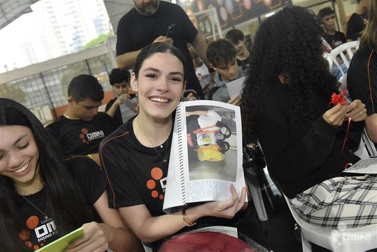 Aluna do OMNI mostrando lembrança emocionada em evento da escola