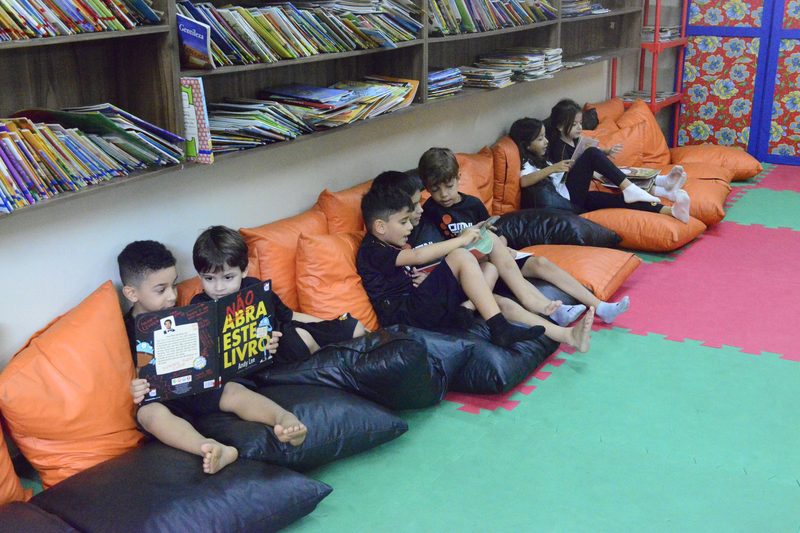 Alunos das Séries Iniciais do OMNI lendo nos pufes da biblioteca